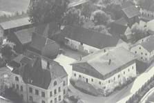 Die Gemeindeverwaltung, damals Schulhaus, 1958. Daneben das damalige Gasthaus Obermeier. Auch dieses alte Holzhaus wurde zwischenzeitlich durch einen Neubau ersetzt. 
(Foto: Gemeindearchiv)